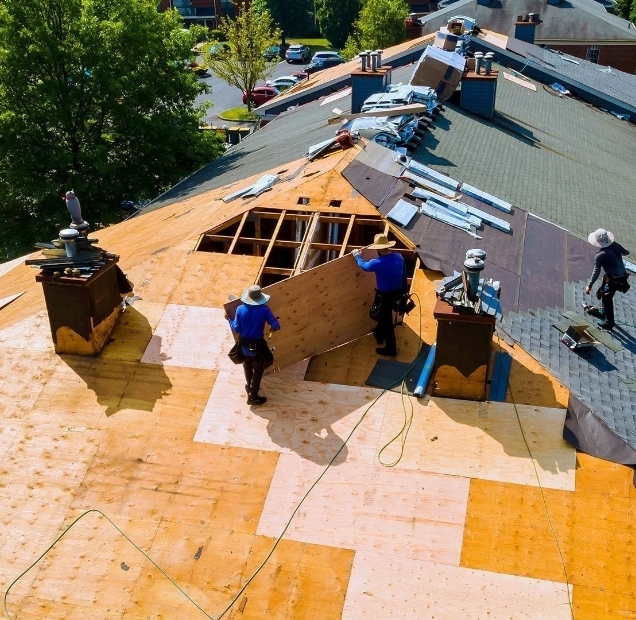 Aerial view of a roof tear off with exposed wood decking and a crew at work