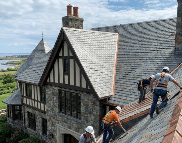 Crew working on the roof of a stone and timber Tudor style house