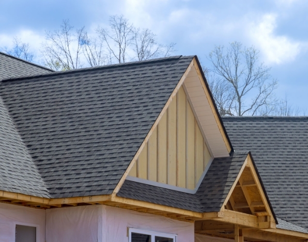 New gray shingle roof on a house under construction with open wood gables